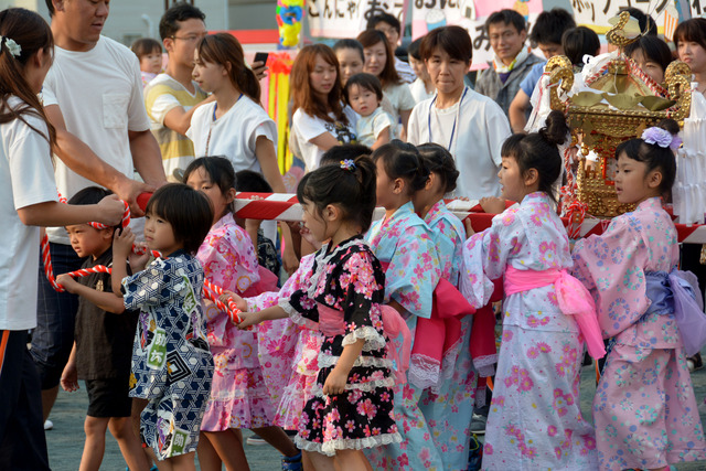 竜王西保育園の園庭にて浴衣や甚平姿の園児たちが神輿をひいている写真